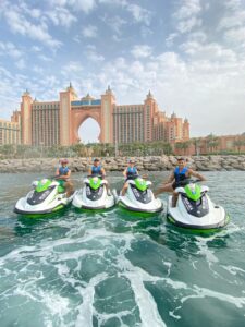 Riders enjoying a thrilling ride on jet skis, with the iconic Burj Al Arab and Palm Jumeirah